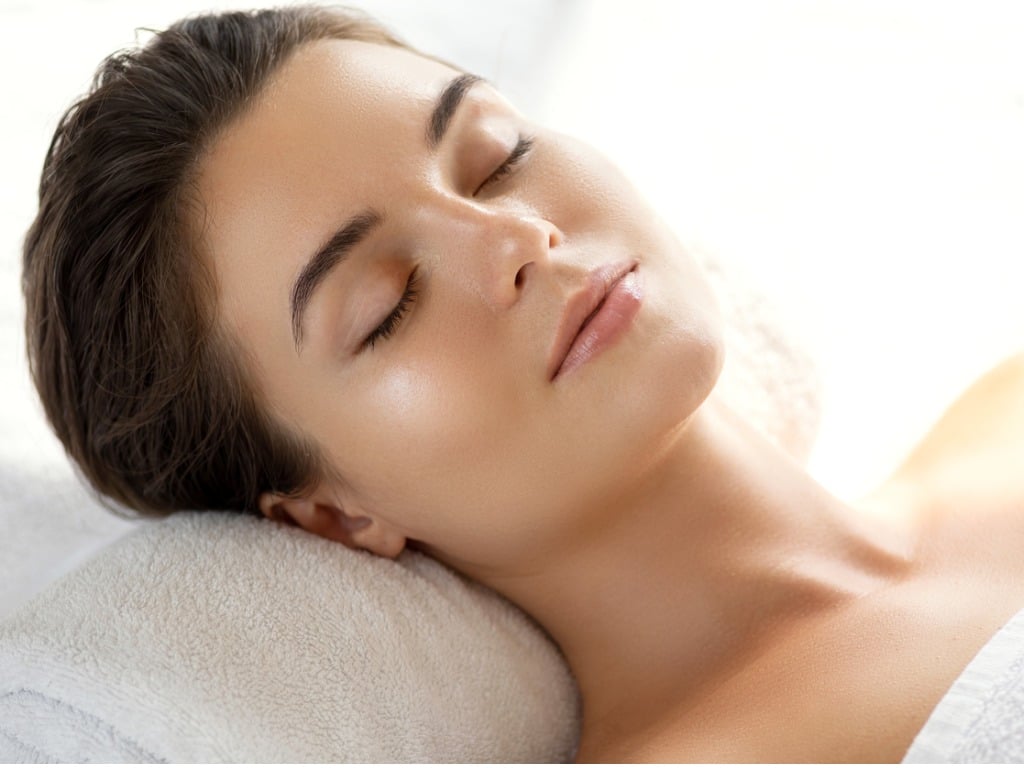 woman with smooth skin lays on a pillow