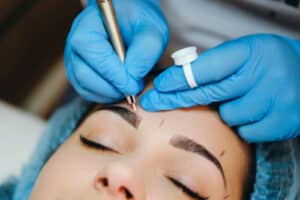 Closeup beautician in gloves doing microblading for eyebrow.