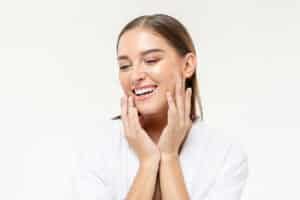 Smiling,Beautiful,Caucasian,Woman,Touching,Her,Face,On,Isolated,Studio