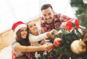 Family gathers around the Christmas tree to decorate it - cosmetic procedures can improve your appearance in photos