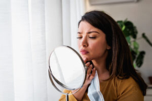 A woman looking in the mirror considering IPL for enlarged pores