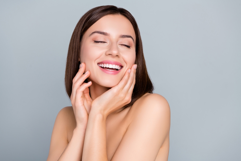 A woman laughing and showing the results of microneedling in Mt. Pleasant