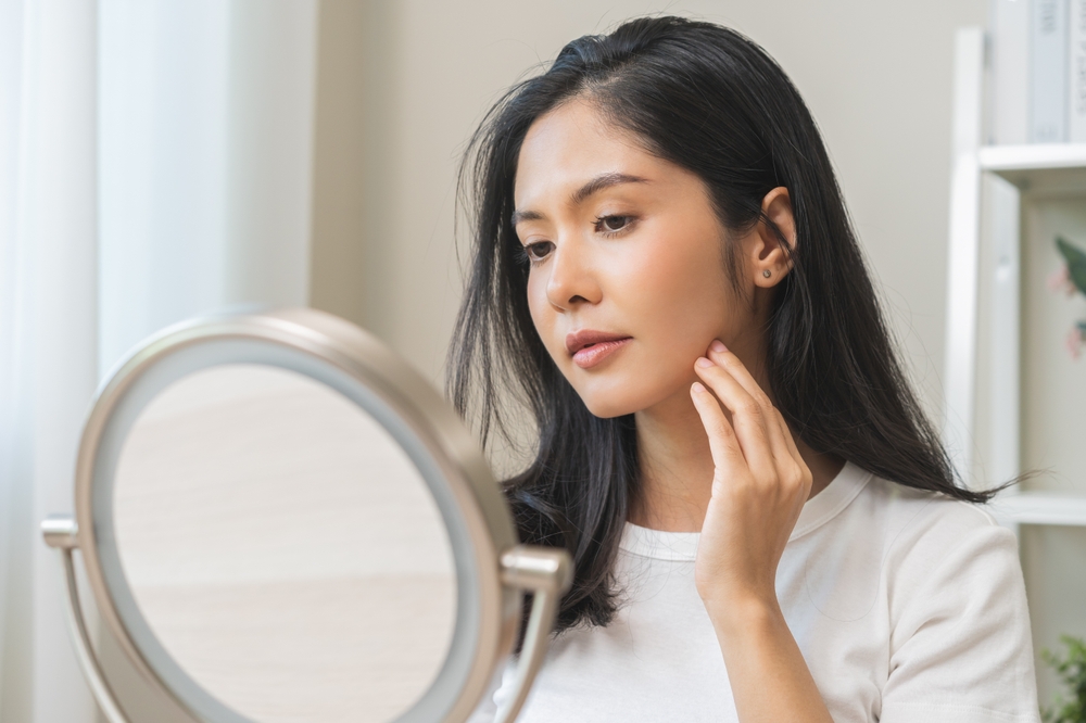 A woman looking in the mirror after microdermabrasion in Mount Pleasant