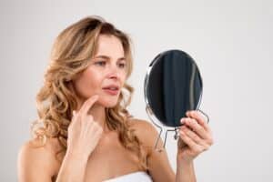 A woman looking at acne scars in the mirror